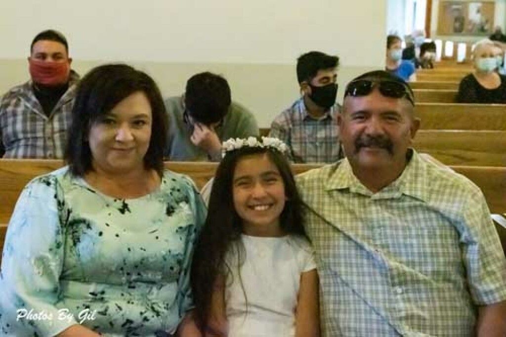A young girl in a white dress and floral headband.