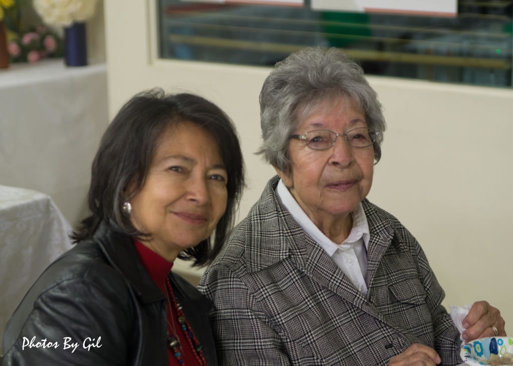 Two women sitting closely, smiling warmly.