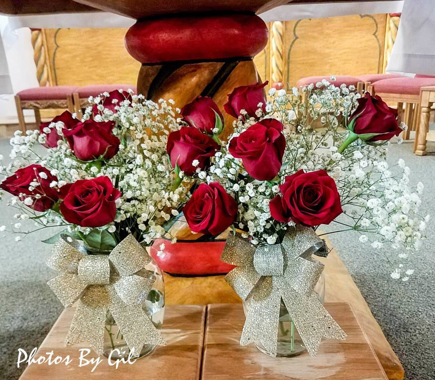 Bouquets of red roses and white baby's breath in glass vases, adorned with silver bows.