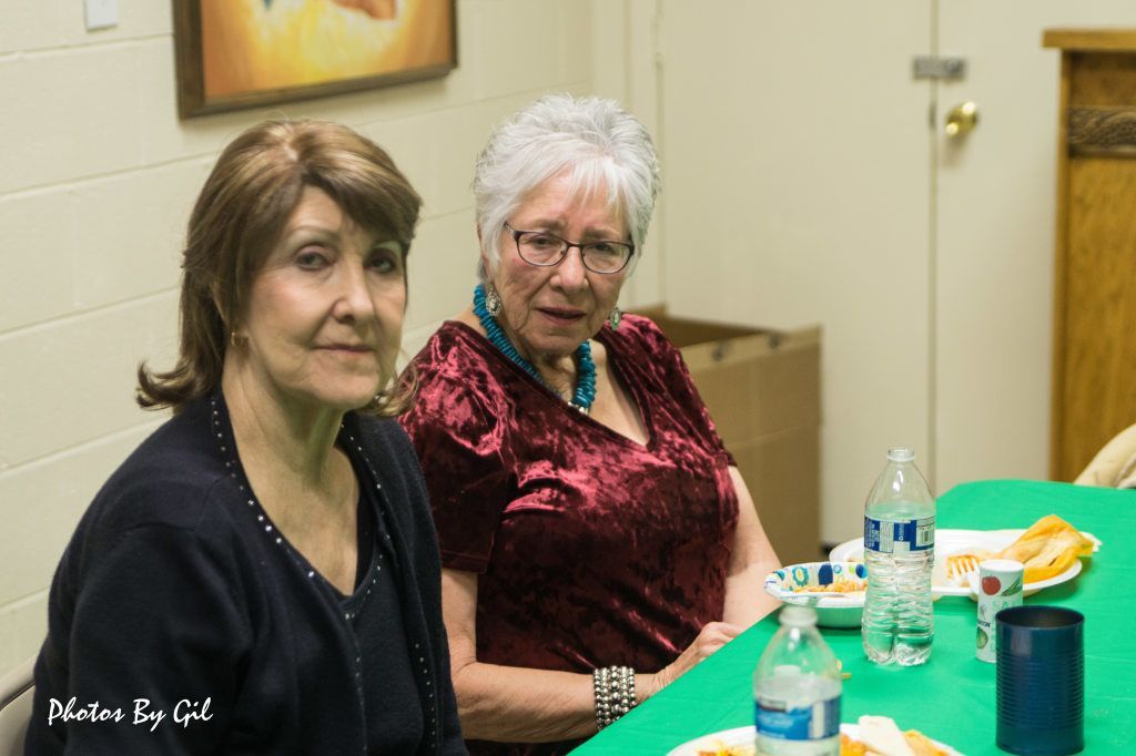 Two older women are seated at a table with a green tablecloth.