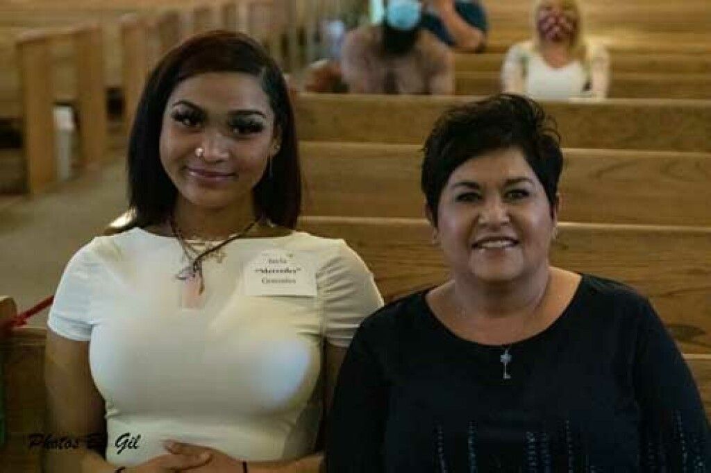 Two people sit closely in a church pew, smiling. 