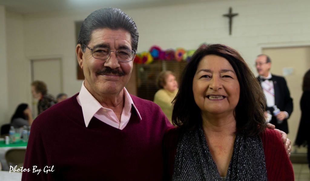A smiling man and woman stand together at a gathering.