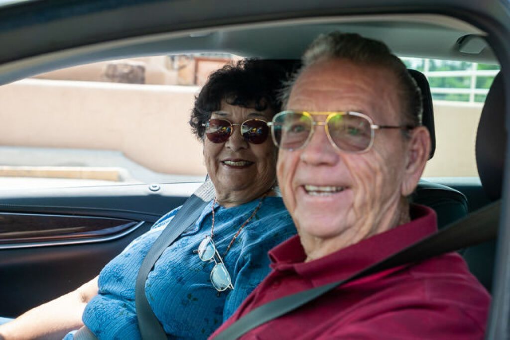 Elderly couple smiling in a car.