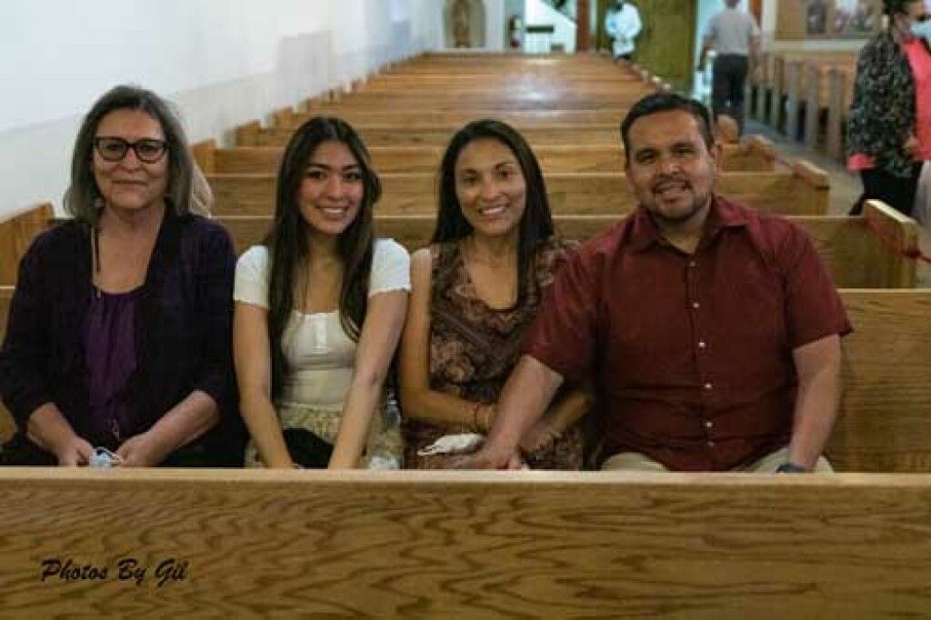 A group of four people sit together in a church pew.