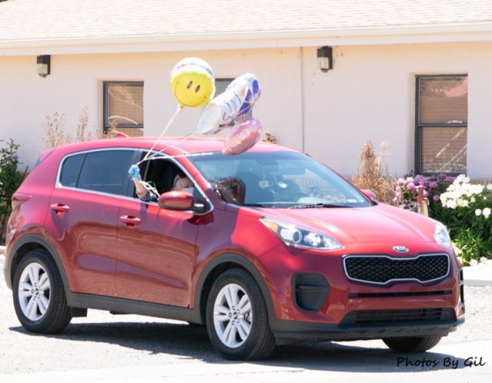 Red SUV with balloons, including a smiley face, emerging from the window.