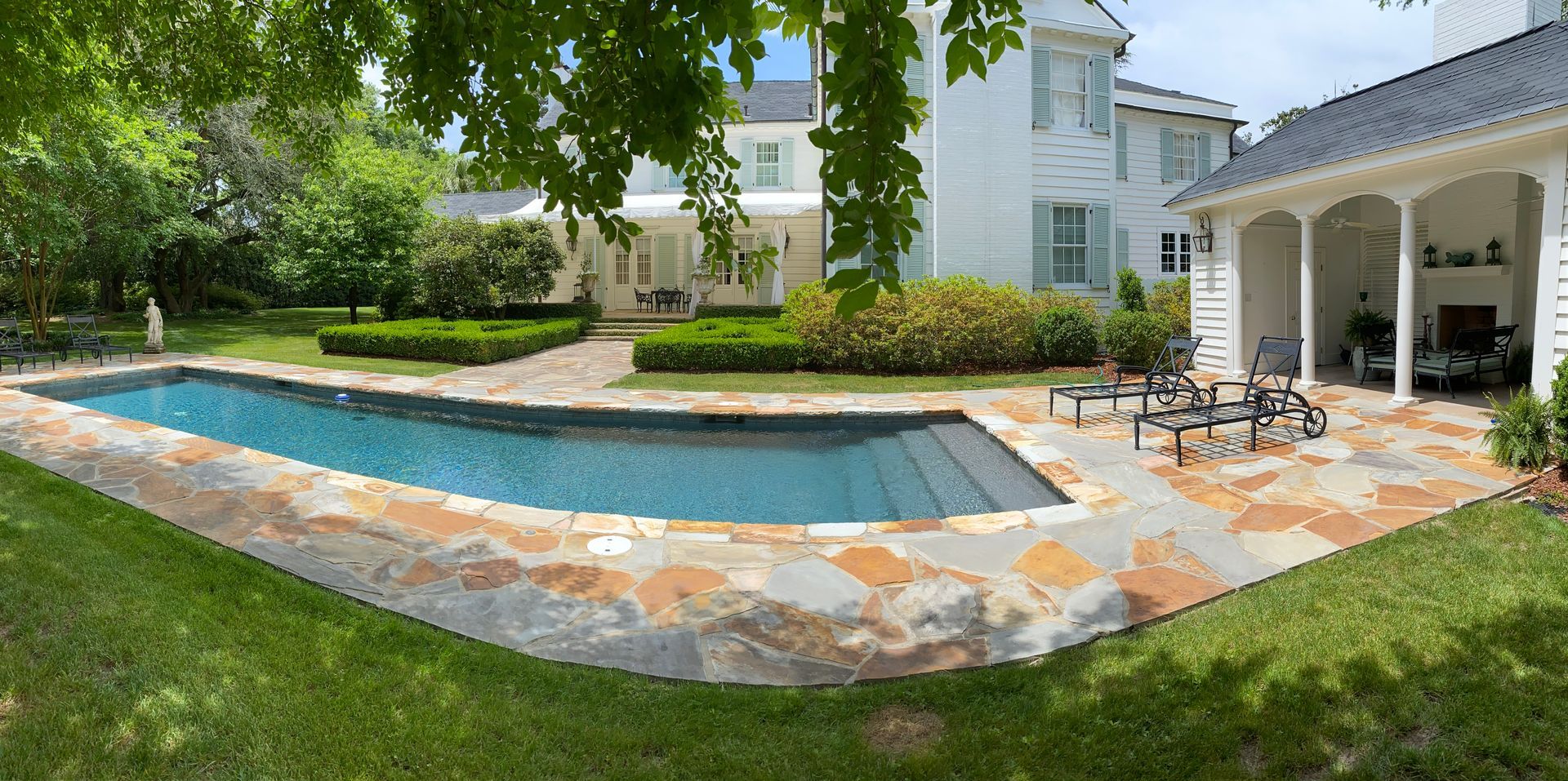 There is a large swimming pool in the backyard of a house.