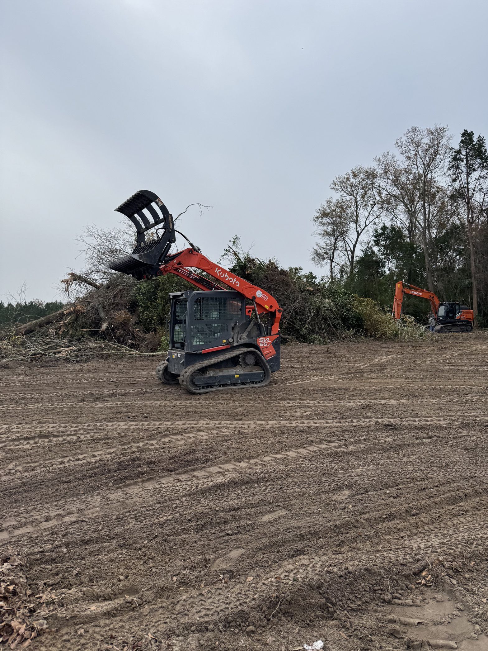 A bulldozer is moving a pile of branches in a field.