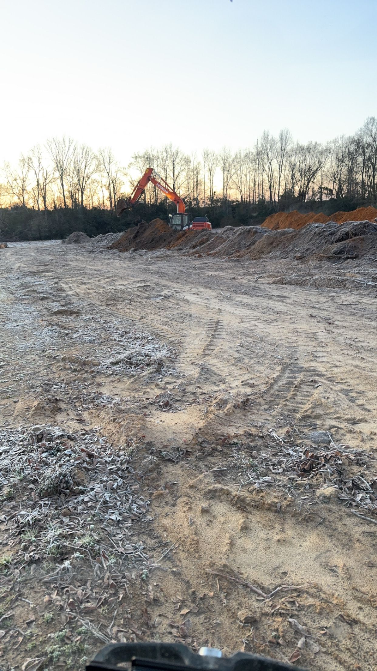 A large dirt field with a bulldozer in the background.