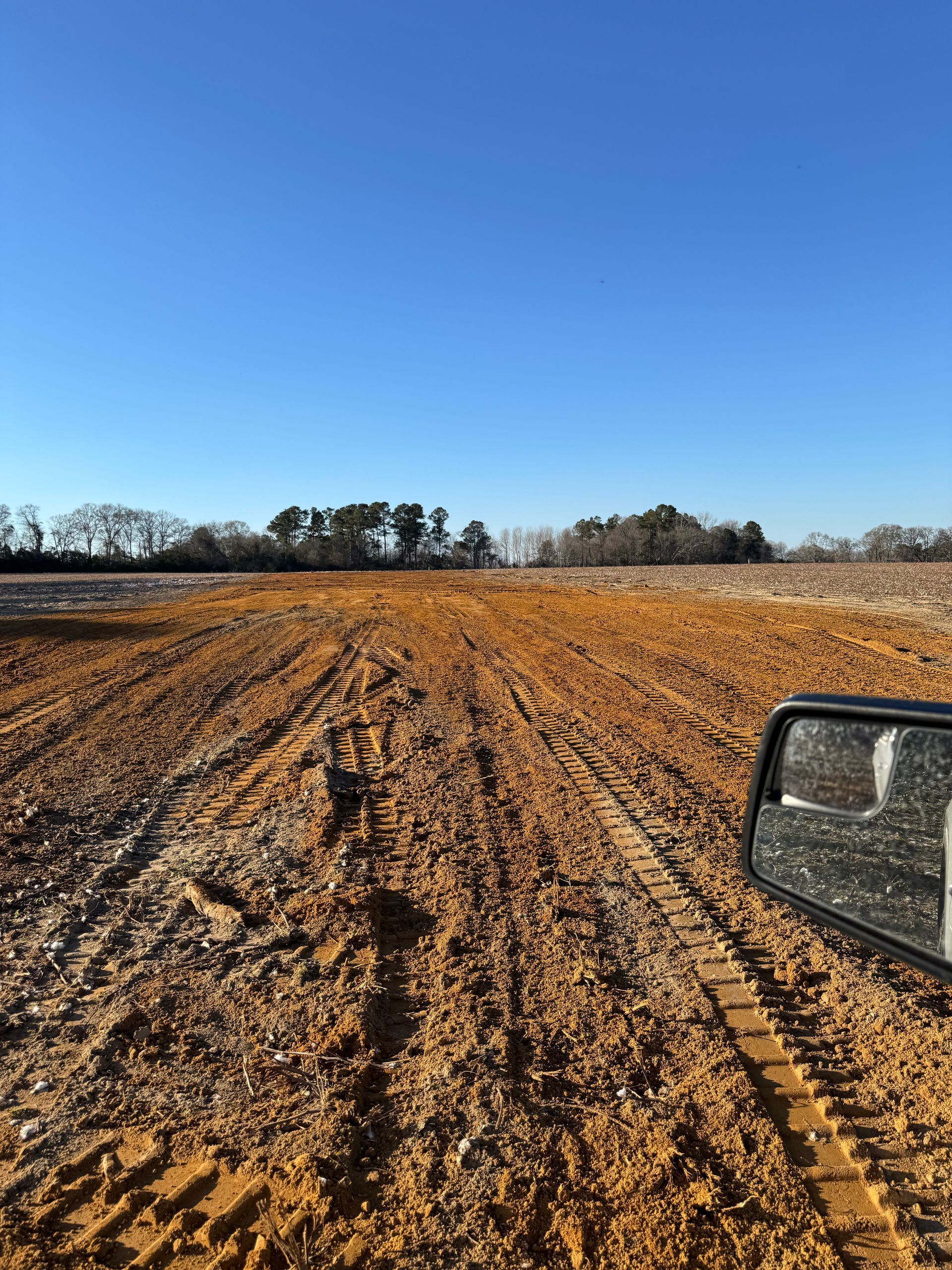 A car is driving down a dirt road in a field.