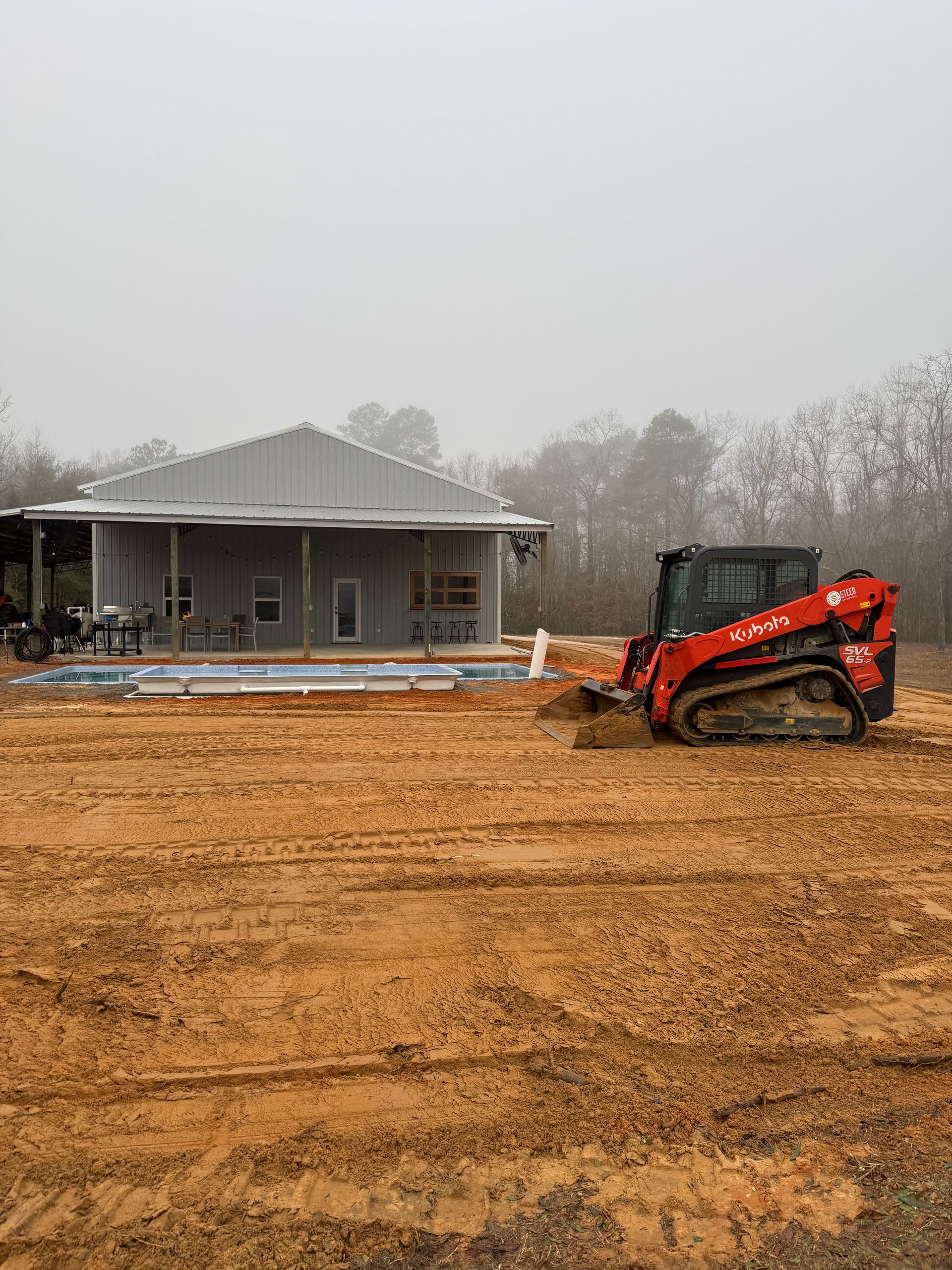 A bulldozer is moving dirt in a field in front of a house.