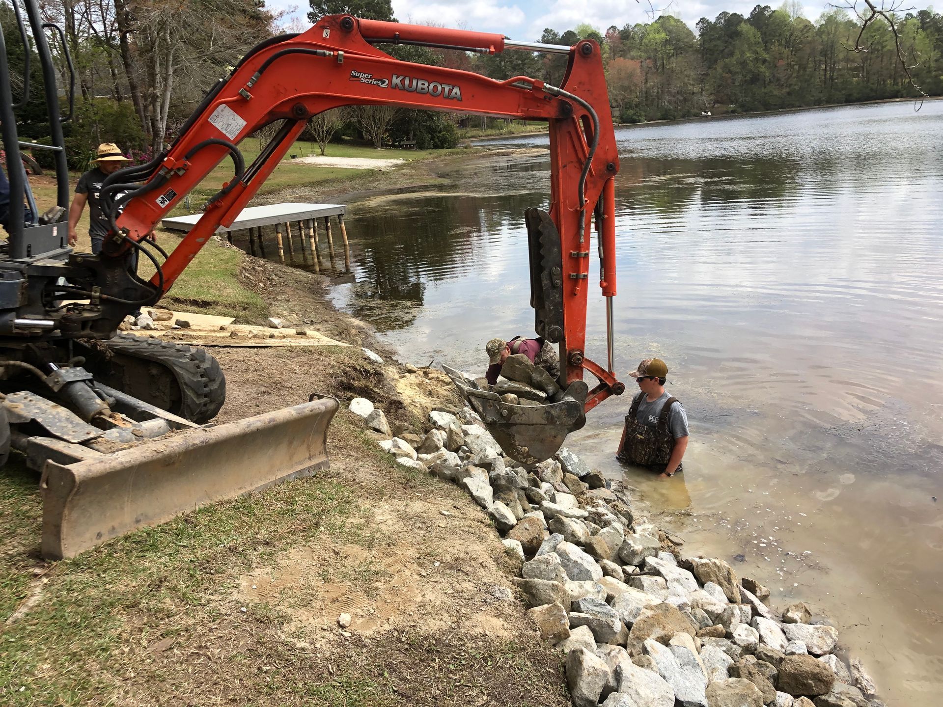 A man is standing in the water next to an excavator.