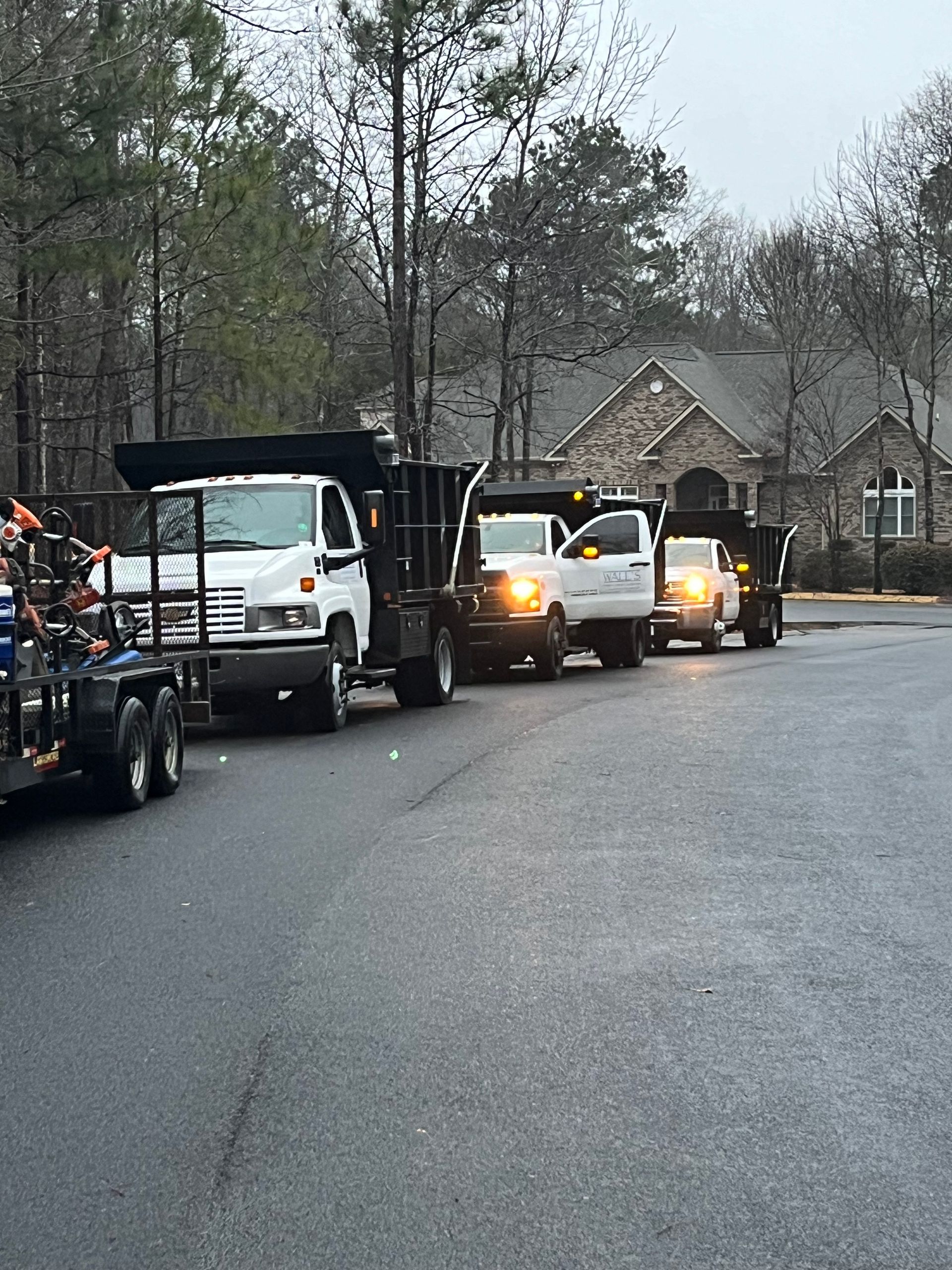 A row of dump trucks are parked on the side of the road