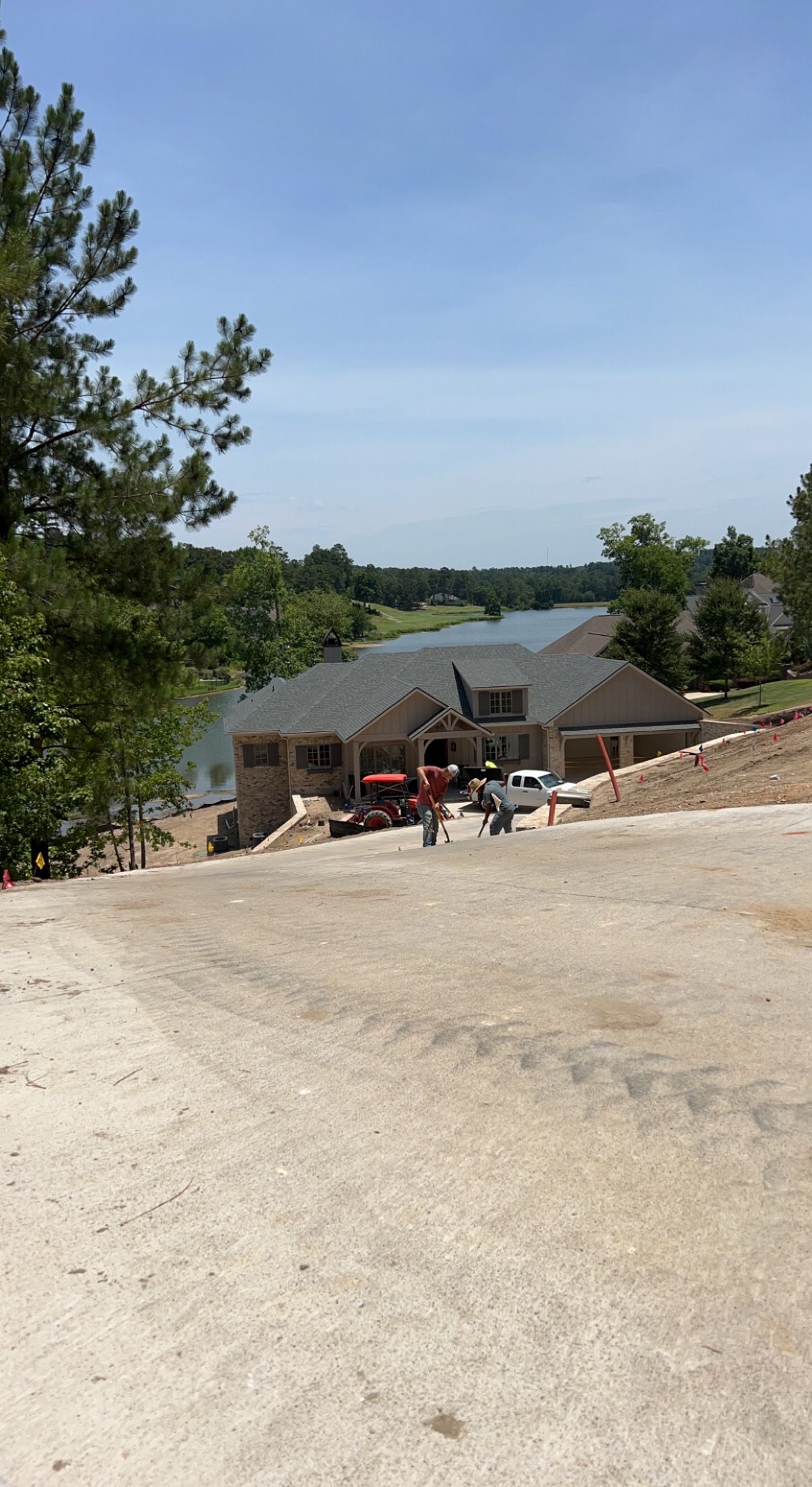 A large house is being built on a hill next to a lake.