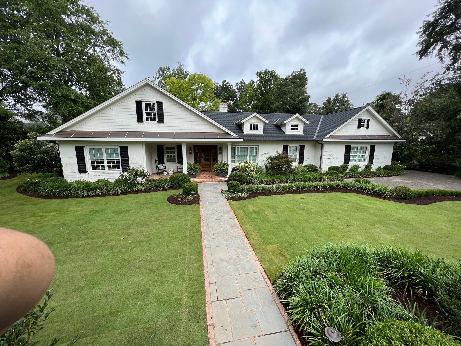 A white house with a black roof and a walkway leading to it
