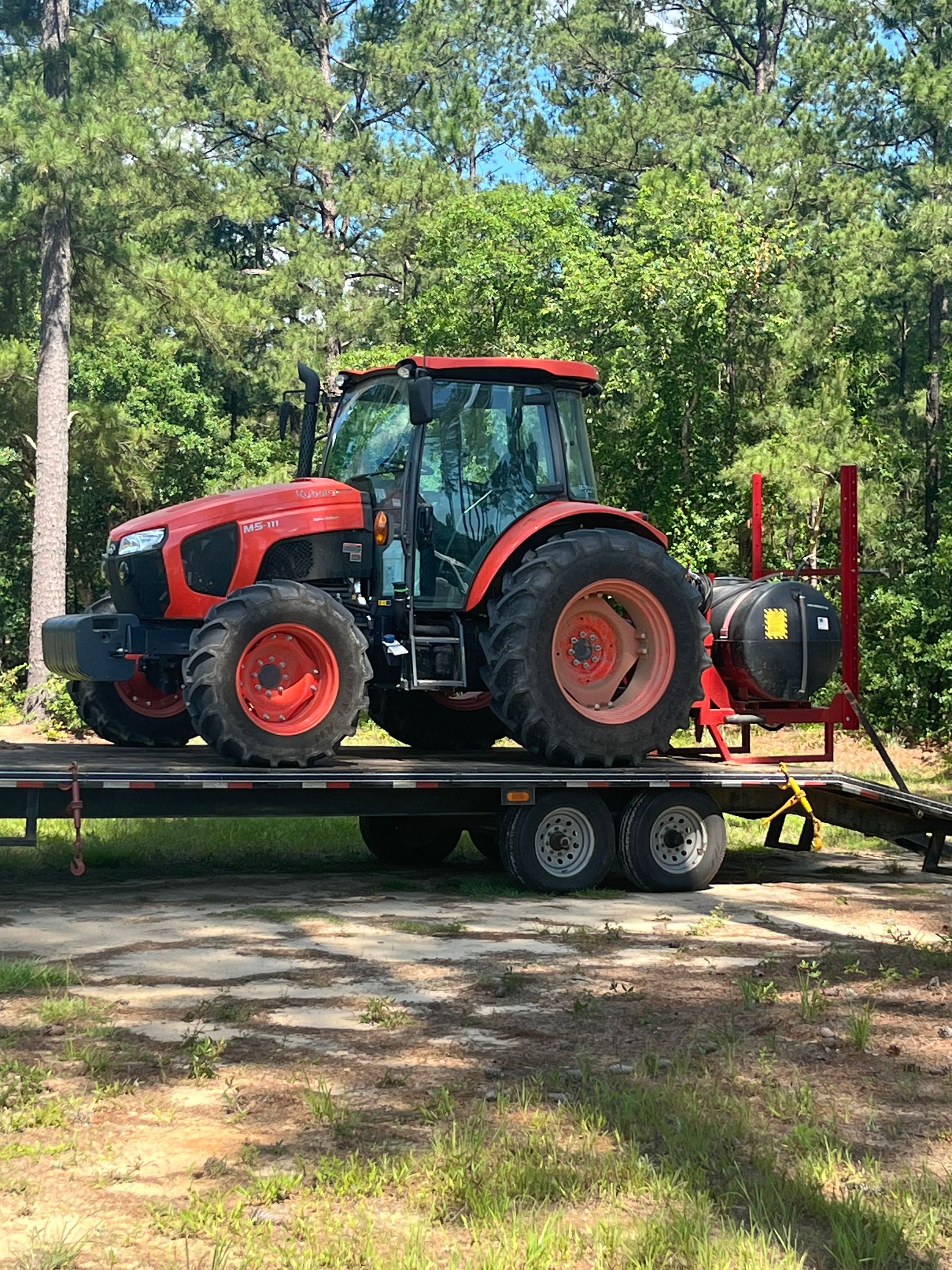 A red tractor is sitting on top of a trailer.