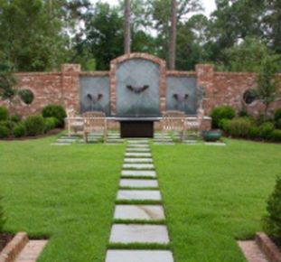 A lush green lawn with a stone walkway leading to a fountain