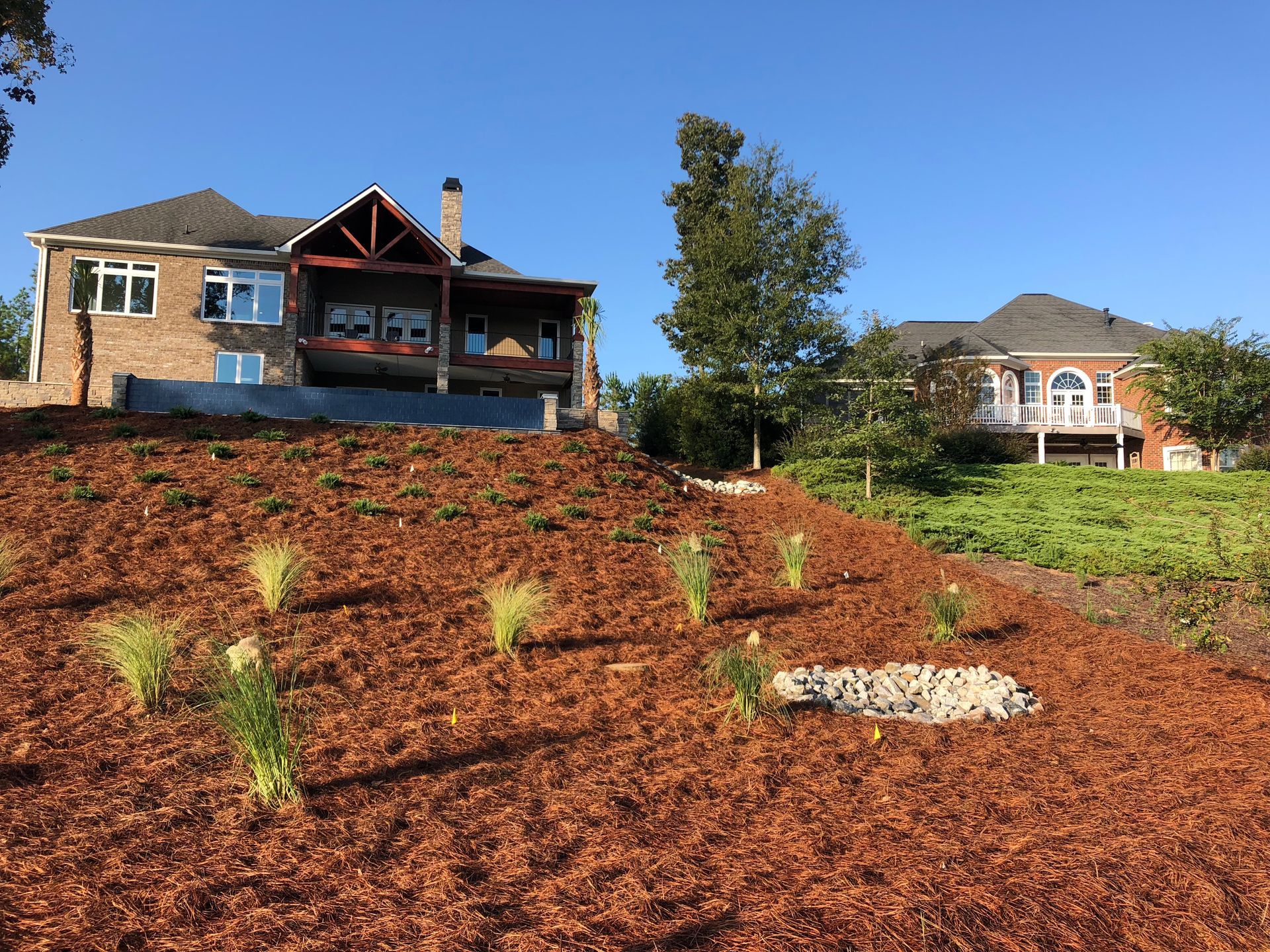 A large house is sitting on top of a hill next to a field of mulch.