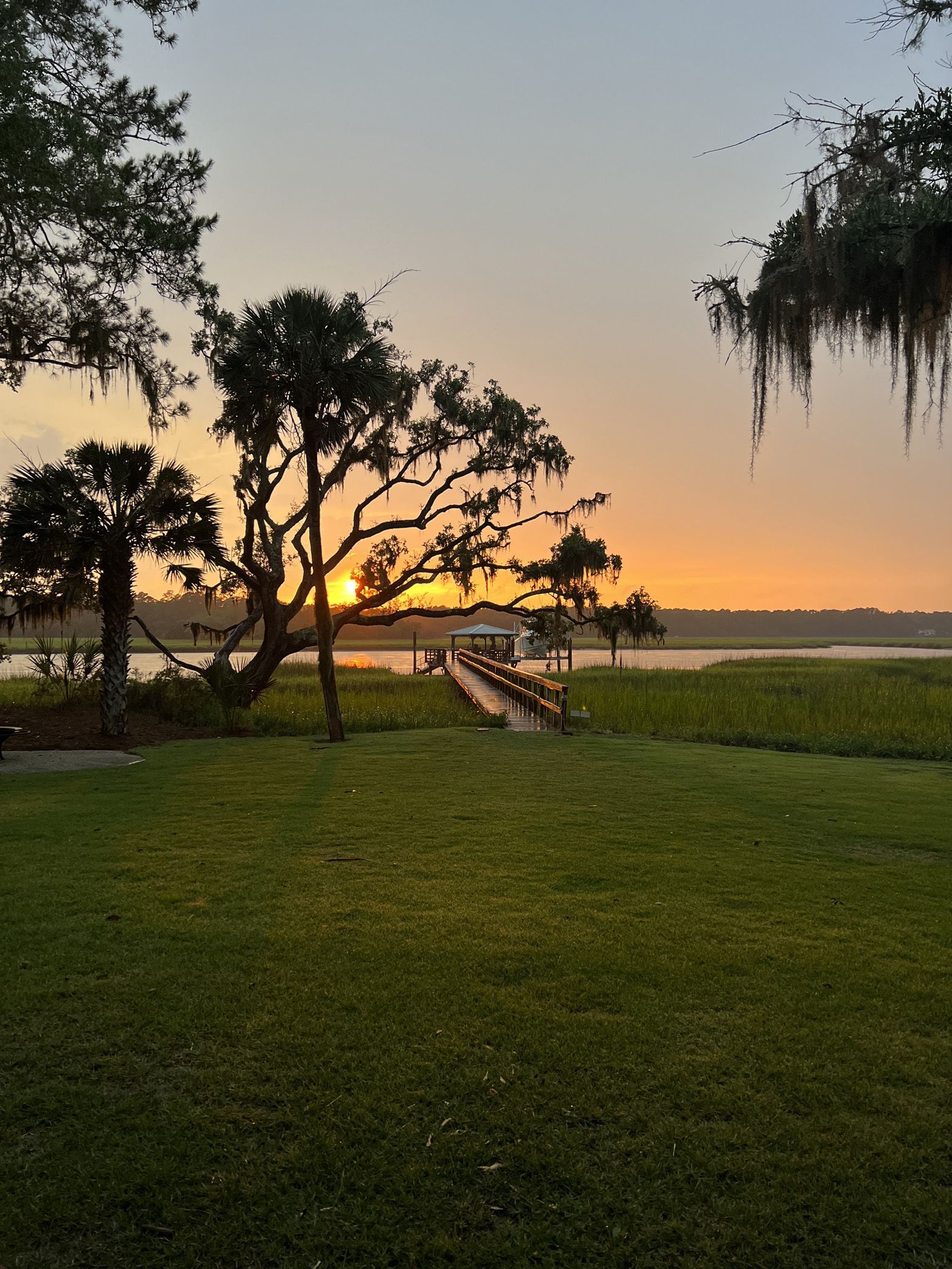 A sunset over a body of water with a dock in the foreground