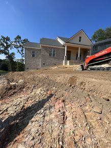 A house is being built on a hill next to a large pile of dirt.