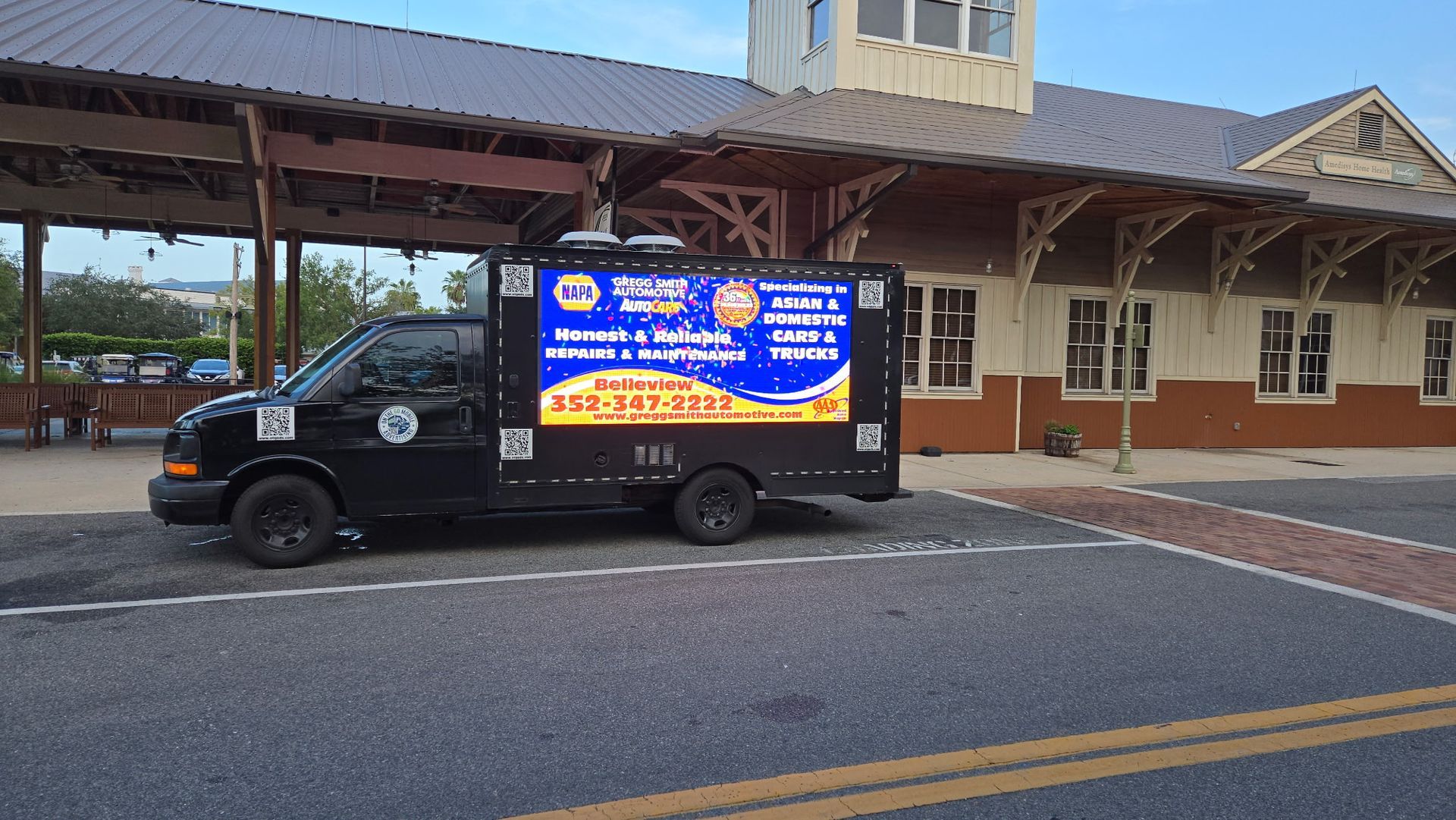 Black van with digital display parked in front of a building.