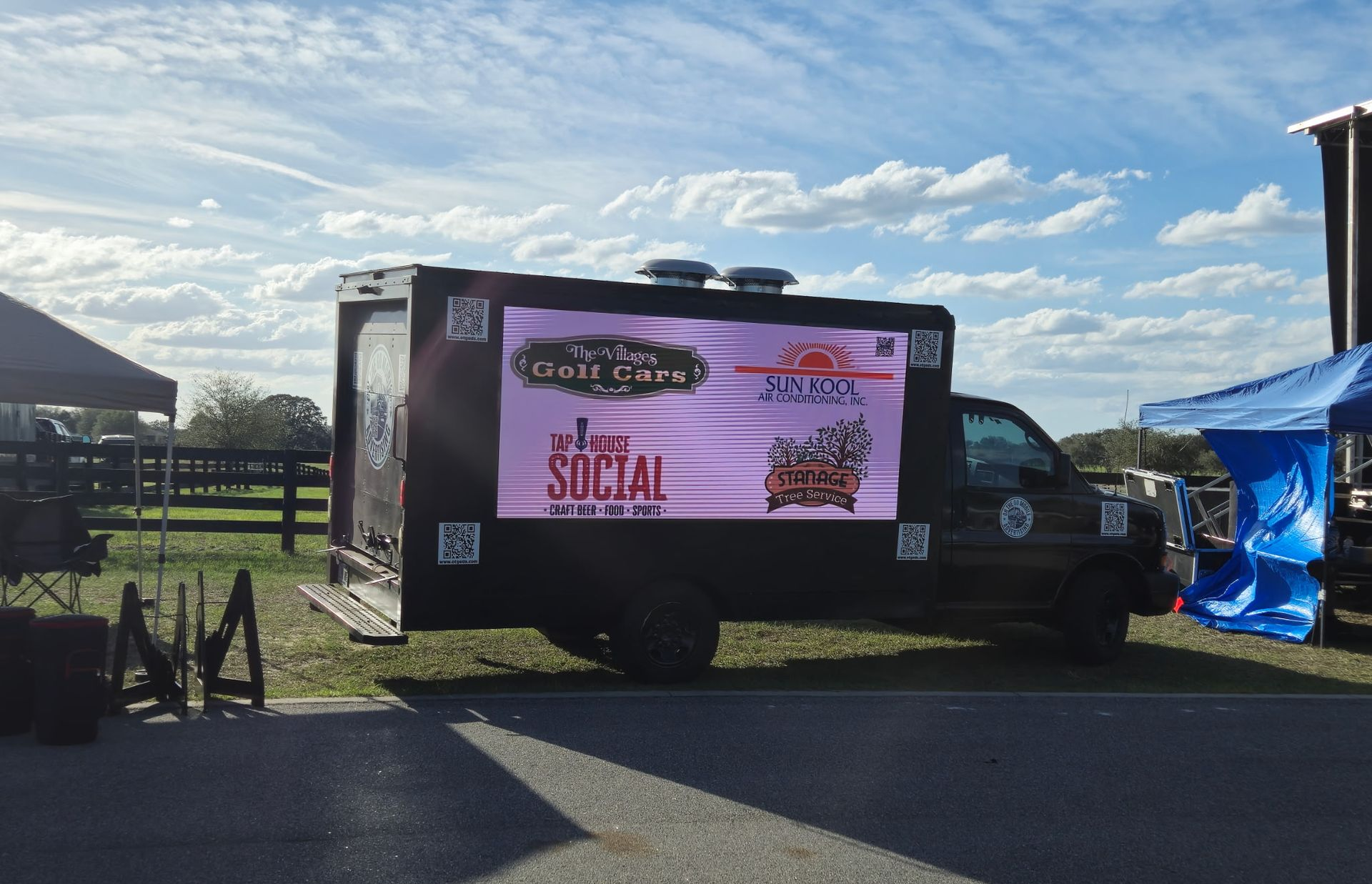 Food truck with a digital display parked outdoors on a sunny day.