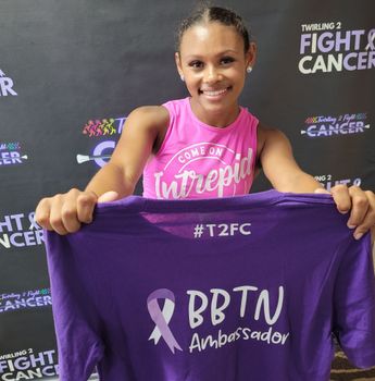 A woman is holding a purple shirt that says bbtn ambassador