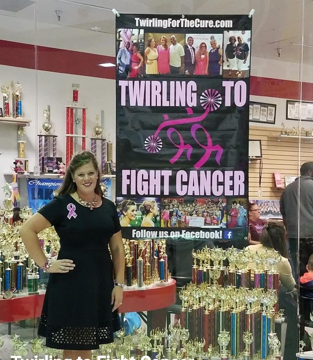 A woman stands in front of a sign that says twirling to fight cancer