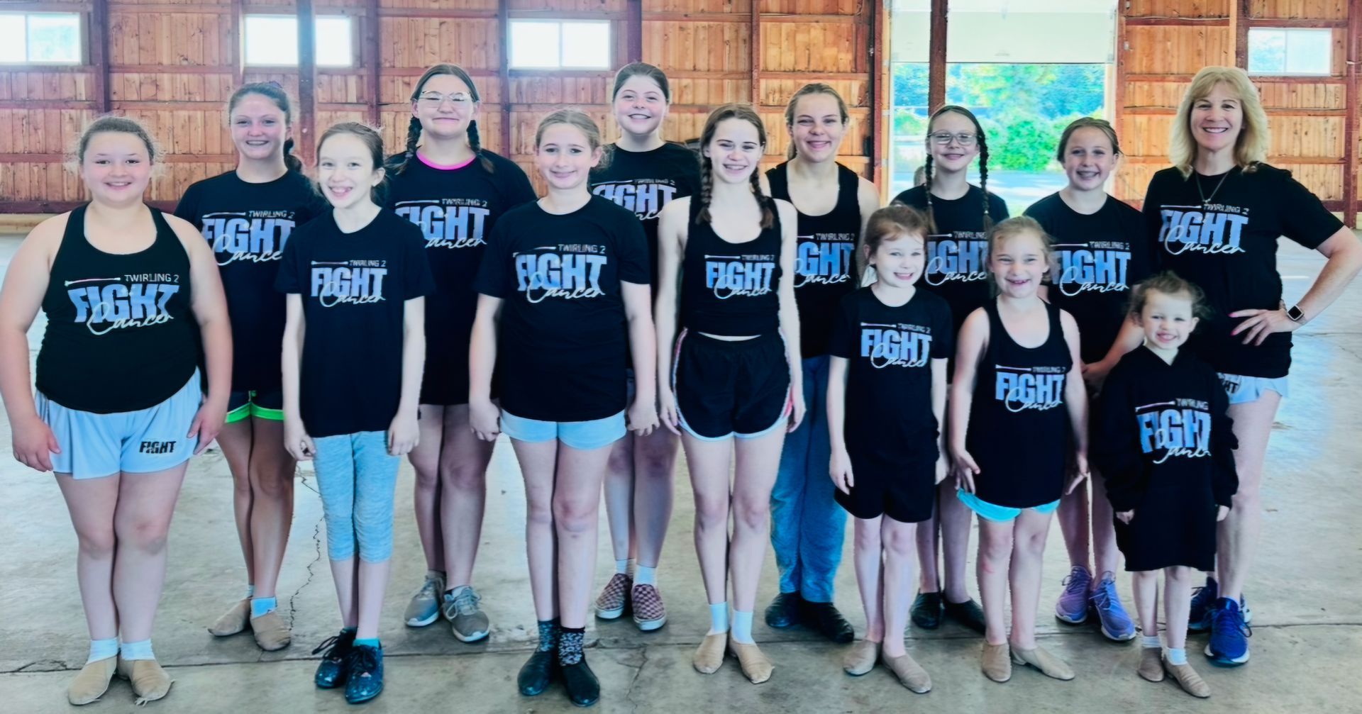 A group of young girls and boys are posing for a picture in a barn.