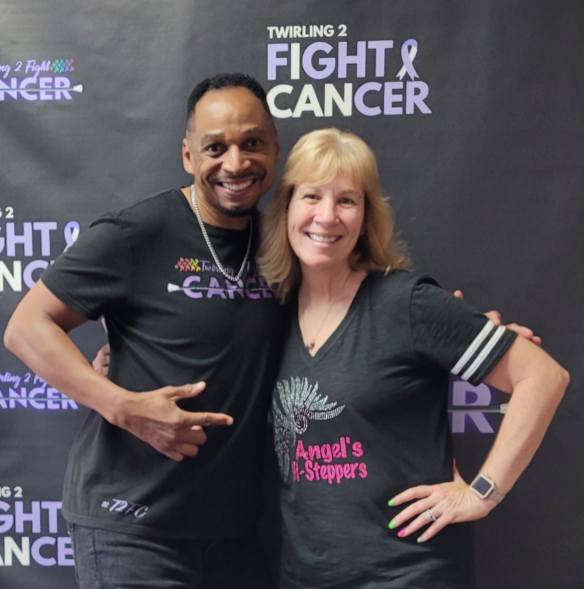 A man and woman are posing for a picture in front of a sign that says fight cancer