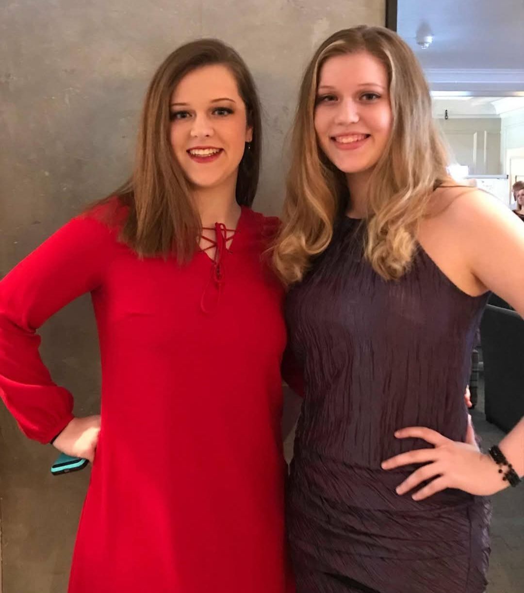 Two women are posing for a picture and one is wearing a red dress