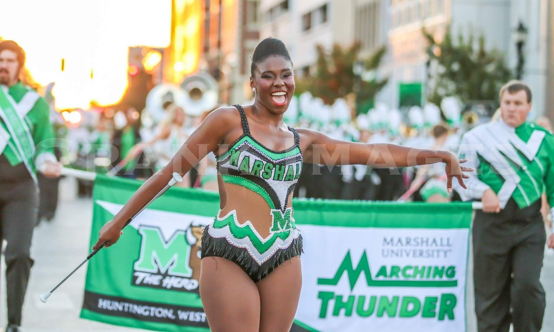 A woman in a green and black outfit is marching in a parade.