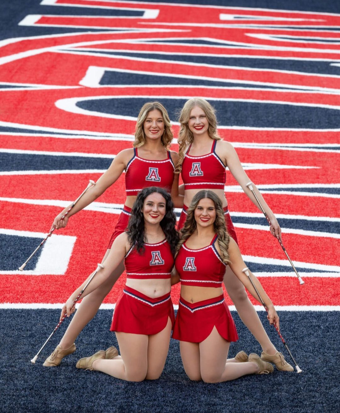 A group of cheerleaders are posing for a picture on a field.