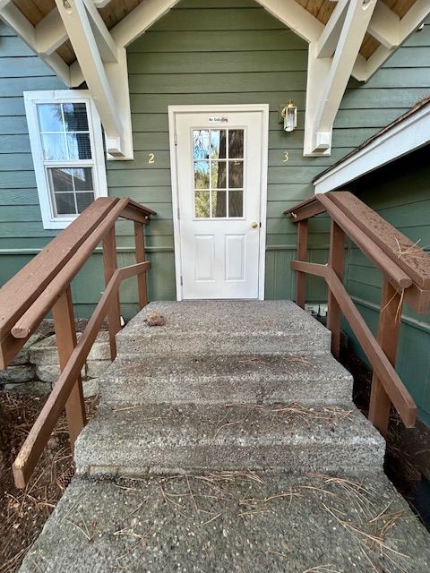 A green house with a white door and stairs leading up to it