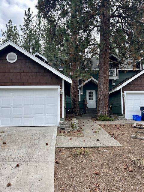 A house with a white garage door is surrounded by trees