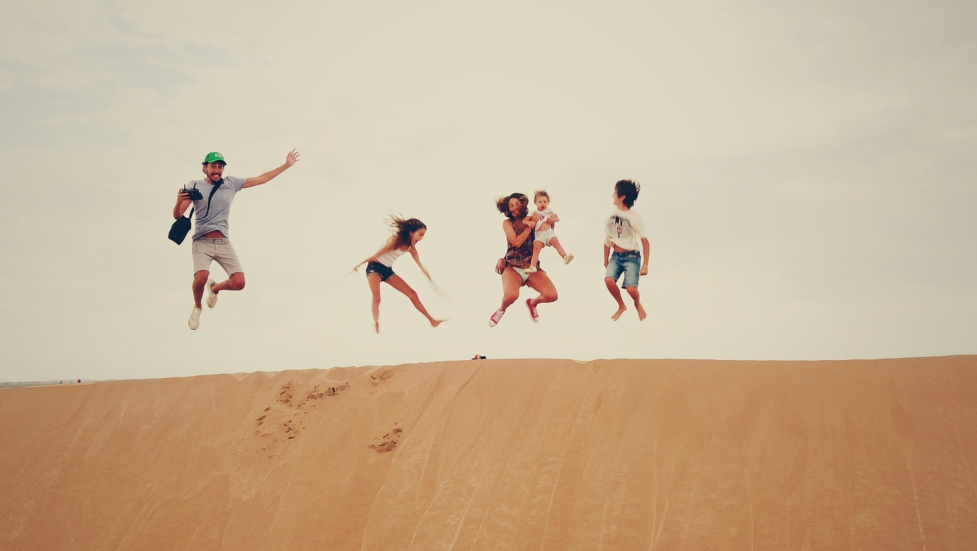 gezin springt in de lucht vanaf zandduin