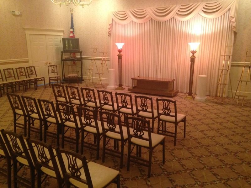 Interior of a funeral home chapel with rows of chairs facing a casket.