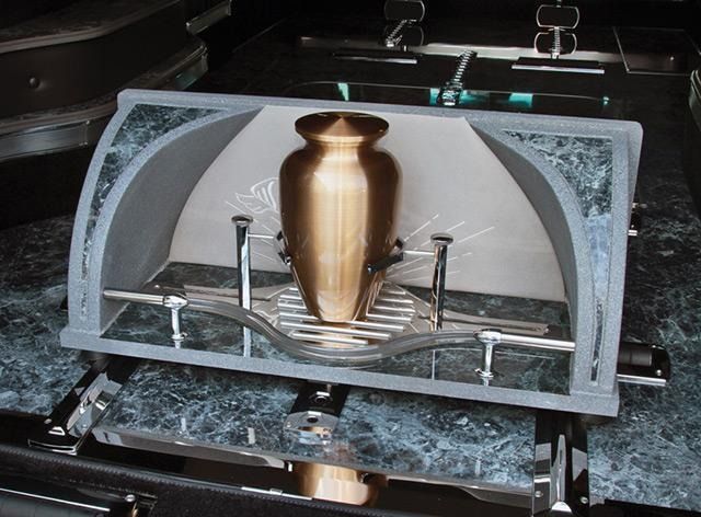 Bronze urn in a gray and marble display inside a hearse.