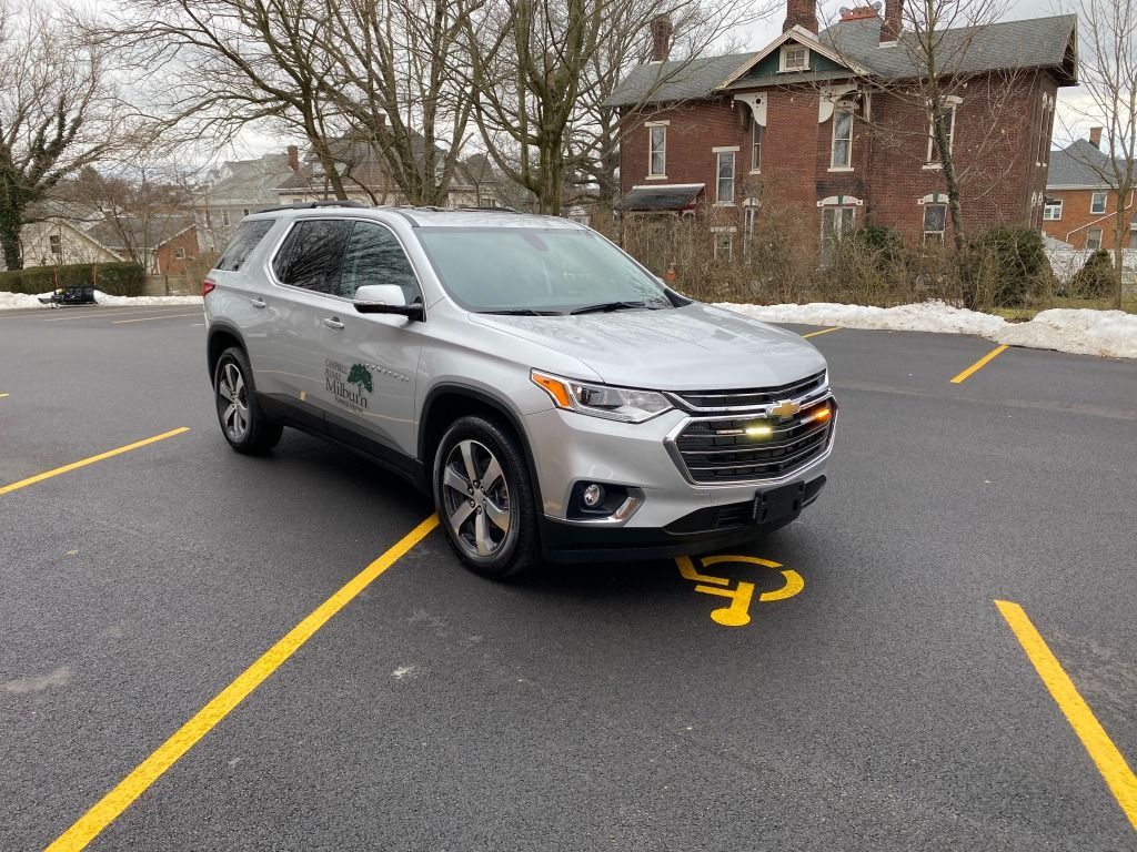 Silver SUV parked in a handicap spot with yellow markings. Building in the background.