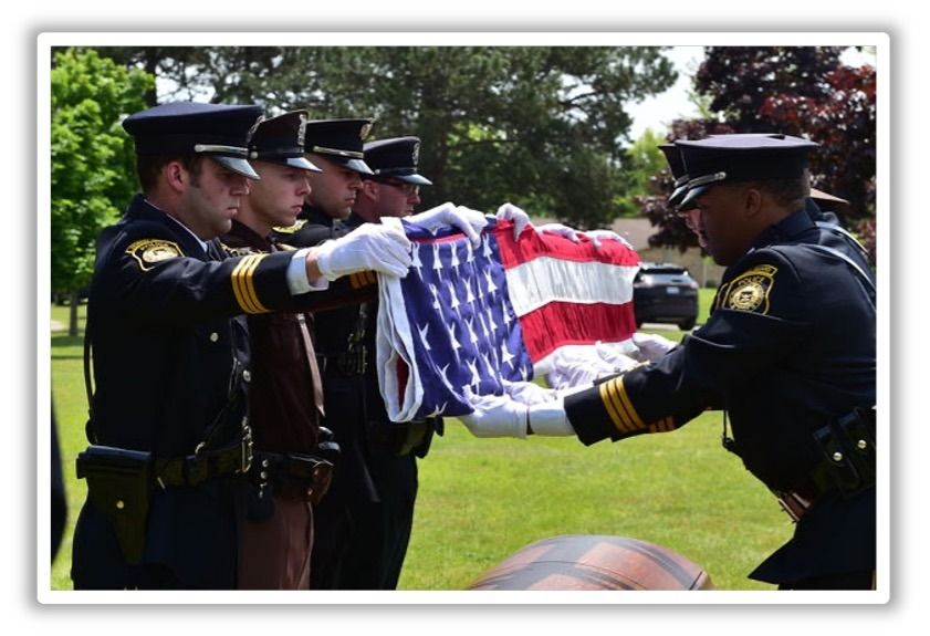 Officers folding an American flag at an outdoor ceremony.