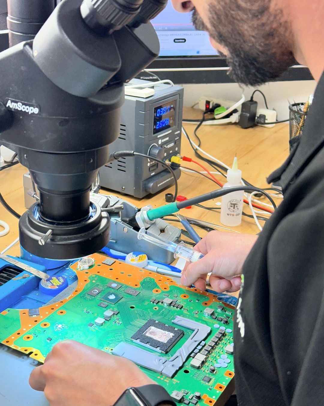 A man is working on a motherboard under a microscope