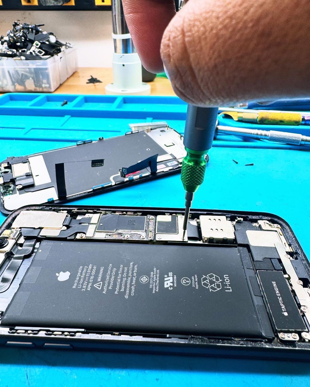 A person is fixing a cell phone with a screwdriver.