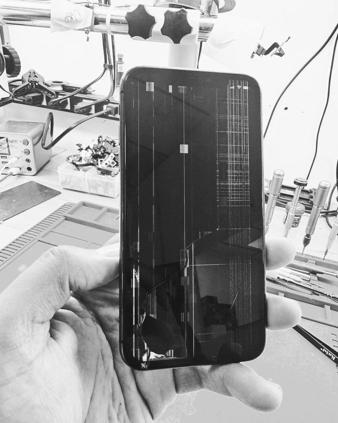 A person is holding a cell phone with a broken screen