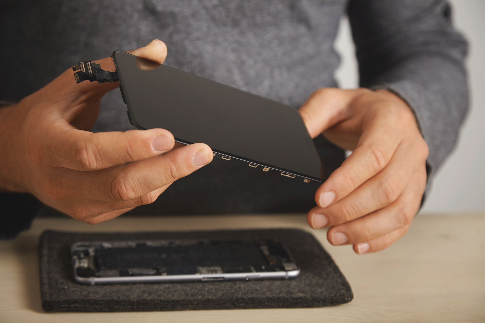 A man is holding a broken cell phone in his hands.