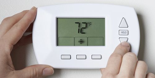 close up of residential digital thermostat being adjusted
