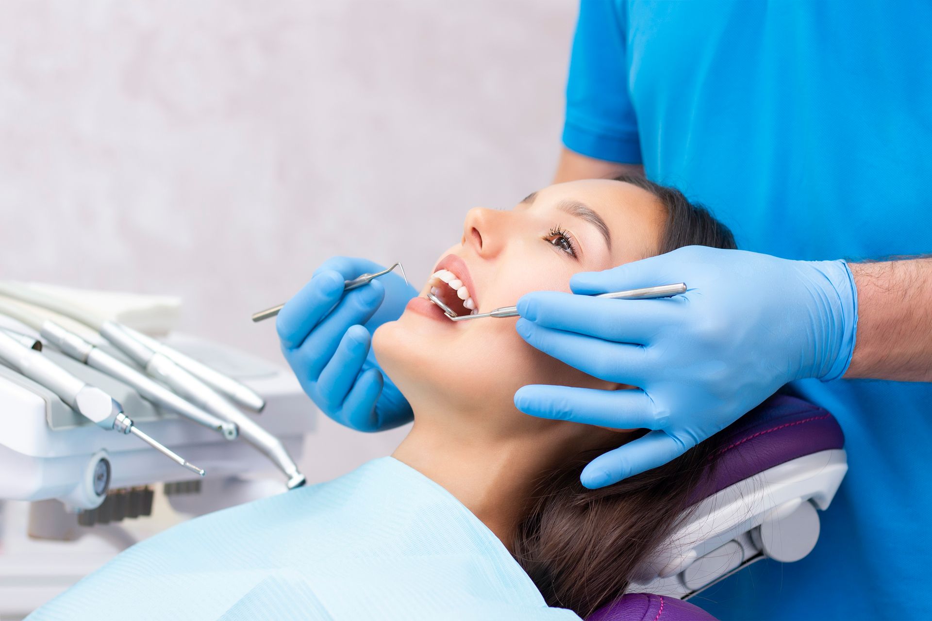 A woman is sitting in a dental chair looking at her smile in a mirror.