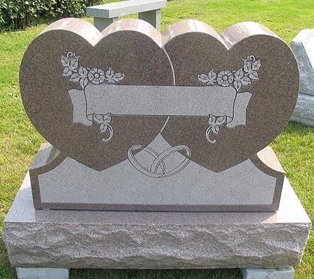 Headstone shaped as two connected hearts, with engraved floral elements and a banner, on a rectangular base.