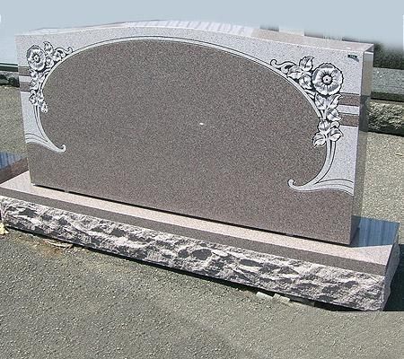 Gray and brown granite headstone with floral etching and oval plaque on a stone base.