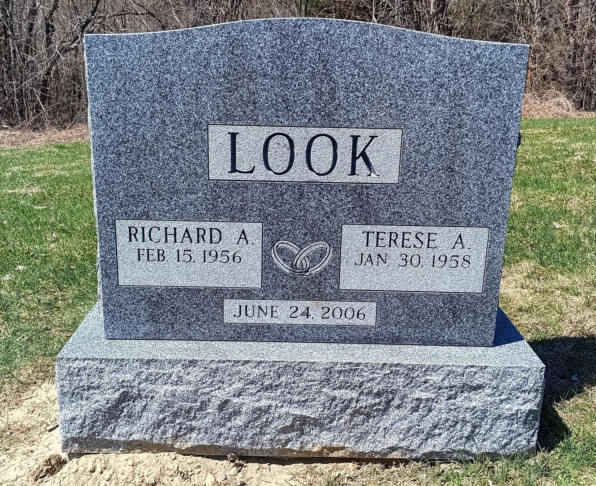 Gray granite tombstone with LOOK engraved at the top, dates and names below, and a heart symbol.