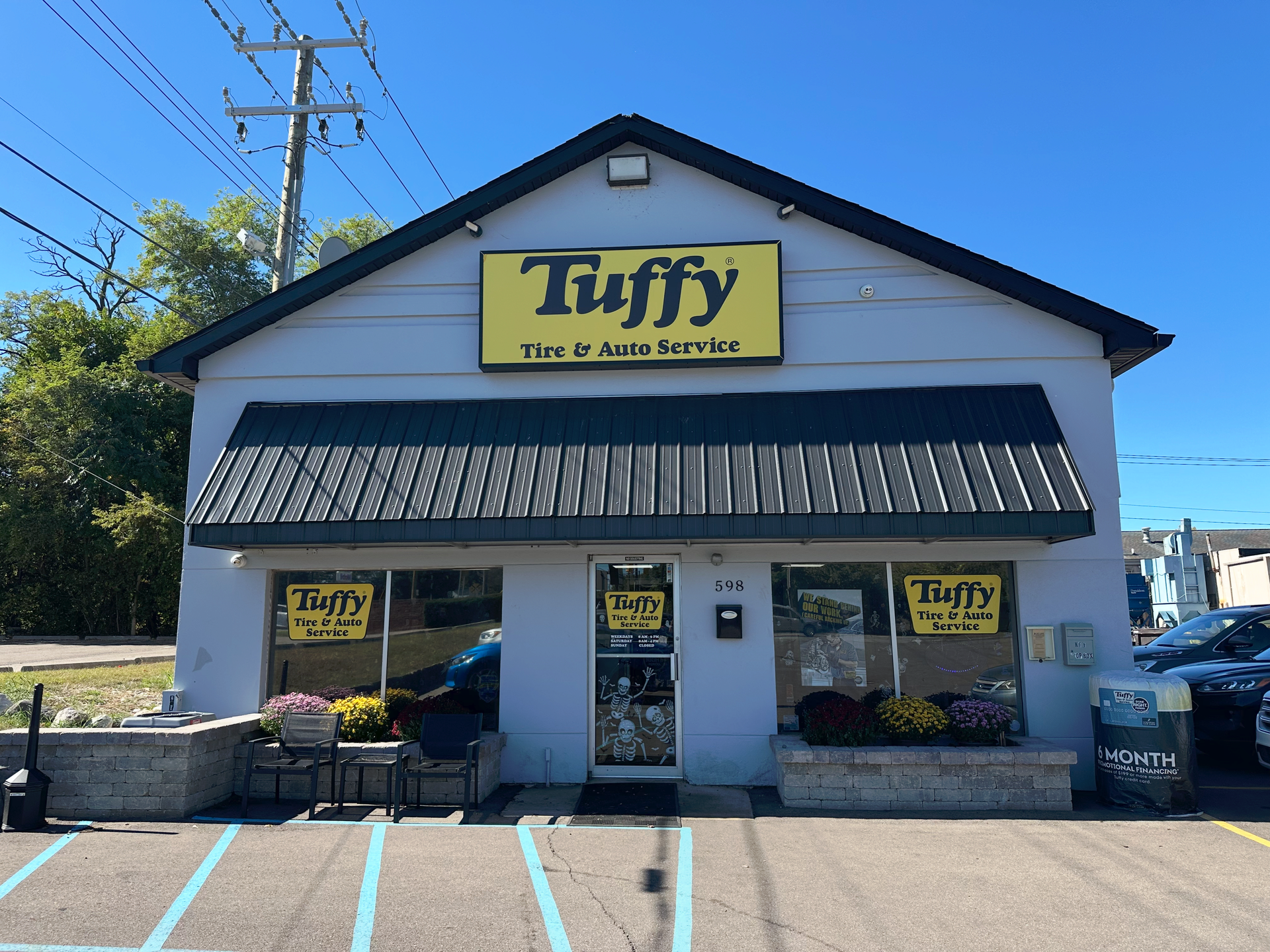 Tuffy Tire & Auto Service shop with a black awning, yellow sign, and blue parking lines.