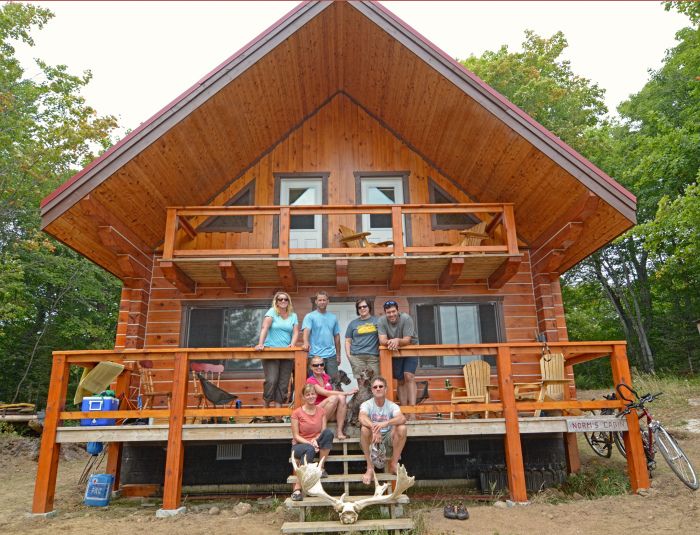 A group of 7 campers on the front porch of Norm's Cabin in the summer.